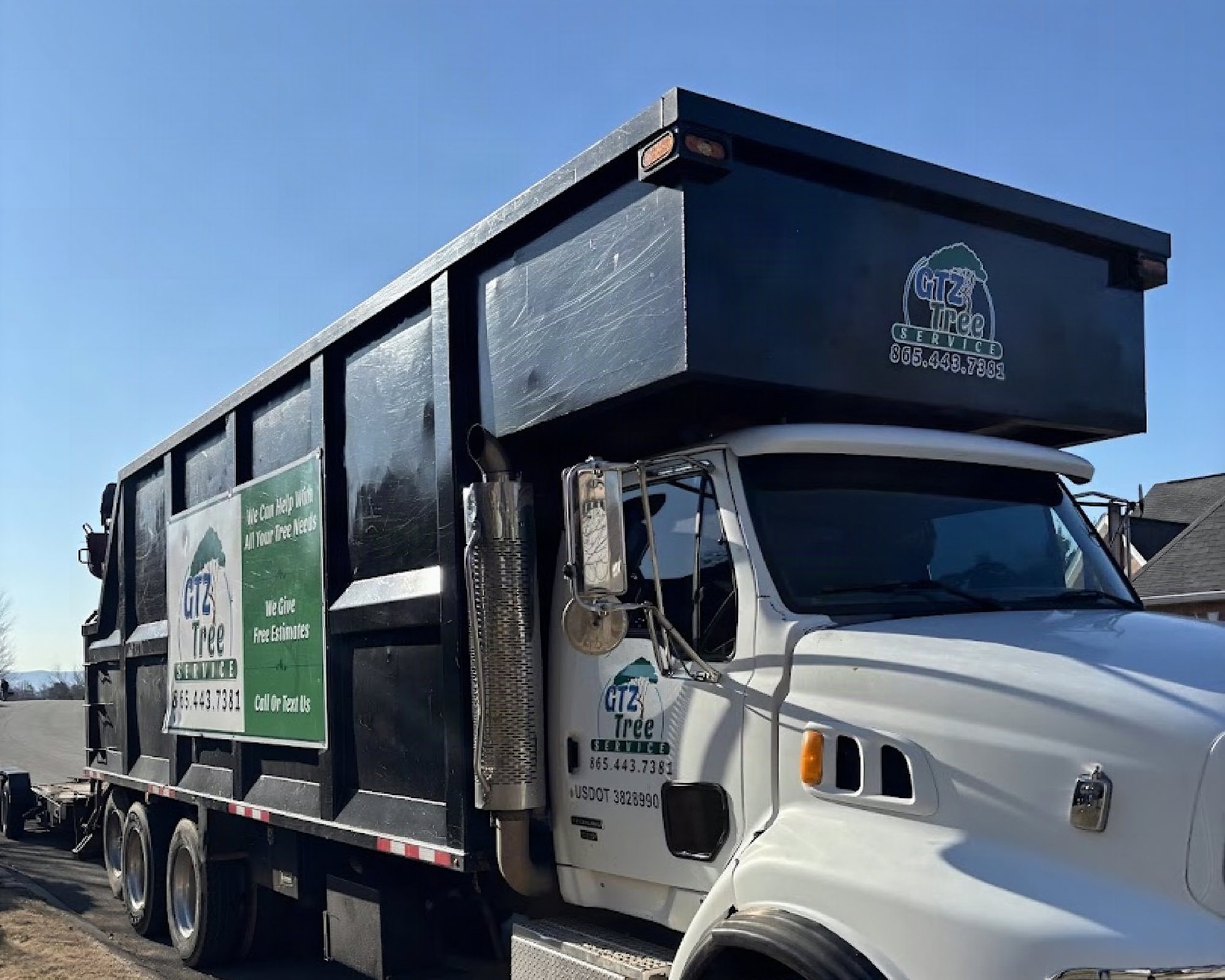 The GTZ Tree Service dump truck parked kerbside, its door and side sign carrying the company name and phone number