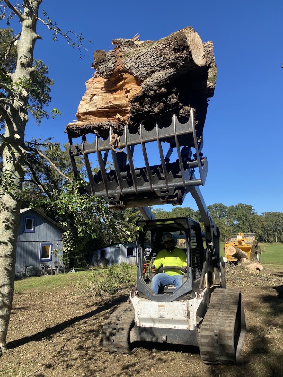 A log loader lifting heavy timber off a cleared site